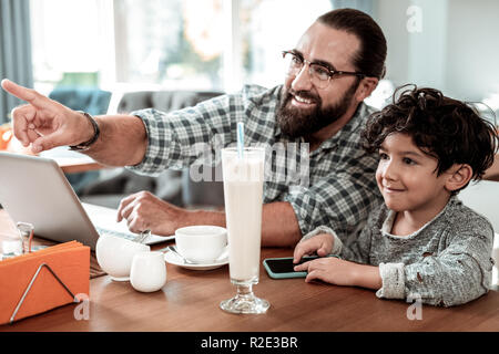 Beaming smiling father and son looking at their mother coming to them Stock Photo