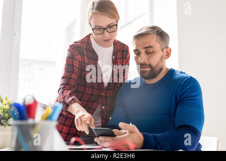 Lady analyzing new smartphone app with colleague Stock Photo