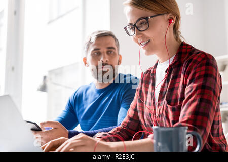 Cheerful female programmer focusing on coding Stock Photo