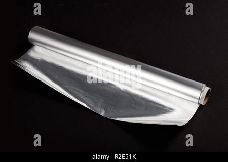 Aluminum foil roll on the black background, close up. Stock Photo