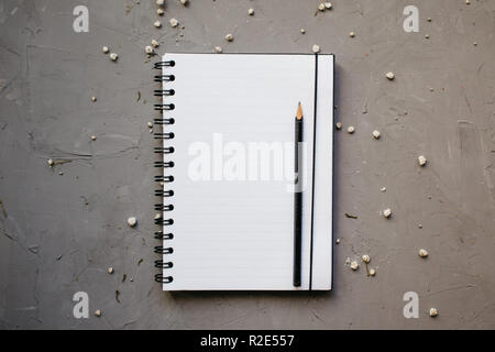 Mock-up with clean notepad and small white flowers, top view. Flat lay of blank notebook and pencil Stock Photo