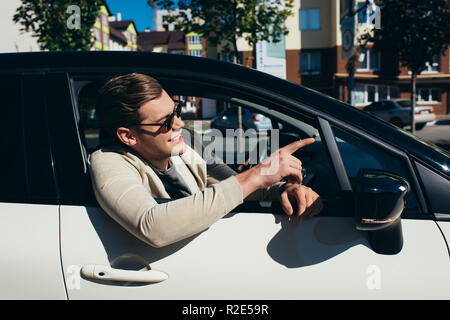 young man leaning out car window of driving automobile Stock Photo