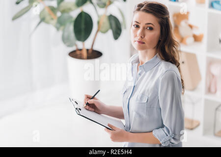 high angle view of adult psychologist writing in clipboard Stock Photo