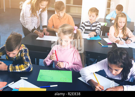 Pretty boys and girls with teacher draw a table game in classroom Stock ...