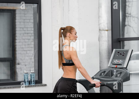 side view of attractive athletic sportswoman training on treadmill in gym Stock Photo