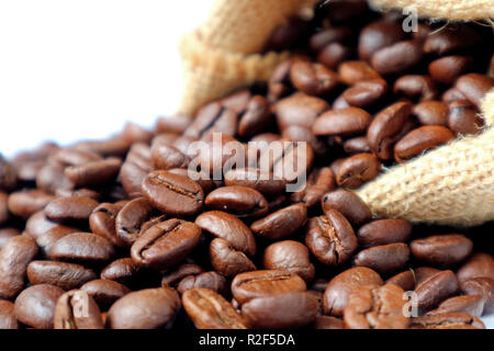Closed up roasted coffee beans scattered from burlap sack on white background Stock Photo