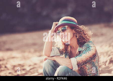 Happy beautiful cheerful caucasian woman middle age sitting at the beach and enjoying the summer time. smile and relax after work. vacation and travel concept with attractive and aged people with colorful lifestyle Stock Photo