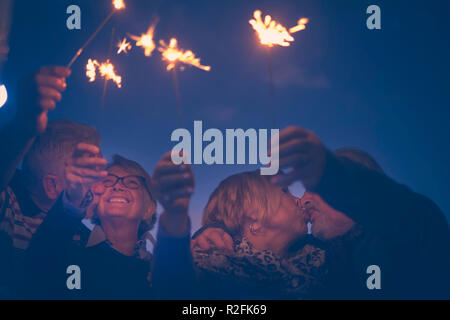 celebration party for holiday night or new year eve 2019. group of aged men and women people with fire sparks. everybody kissing and having a lot of fun by night Stock Photo
