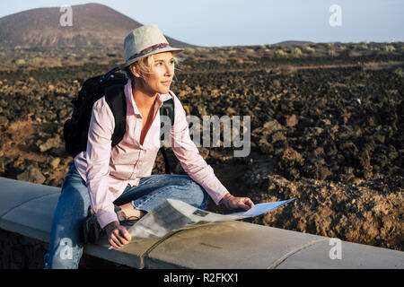 young beautiful lonely traveler woman looking at the map to choose her next destination and adventure. backpackers life and wanderlust feeling concept. cheerful nice blonde in alternative vacation lifestyle