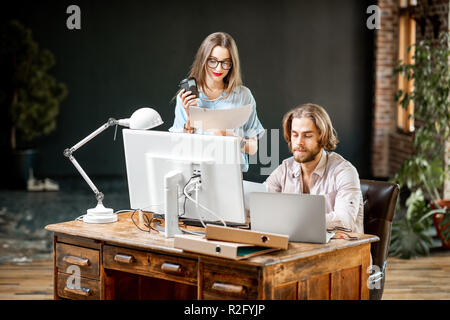 Young colleagues dressed casually working together with computers at the modern office interior Stock Photo