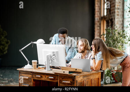 Group of young multi ethnicity coworkers dressed casually working together with computers and documents at the modern office interior. Image with copy space Stock Photo