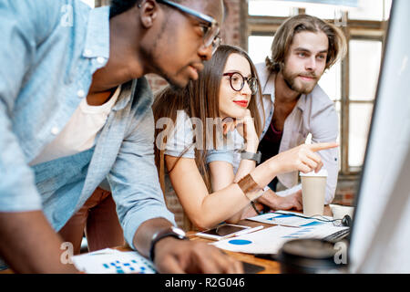Group of young multi ethnicity coworkers dressed casually working together focused on the computer monitor indoors Stock Photo
