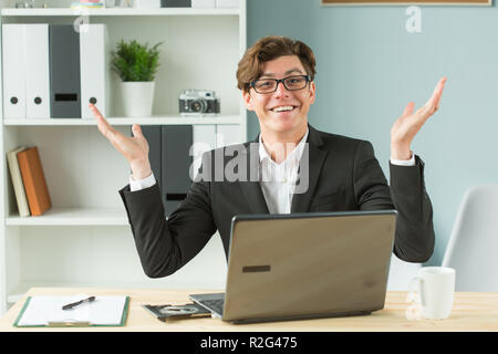 Technologies, emotions and business people concept - handsome man spreading his hands while he is working at computer, because he has some problems Stock Photo