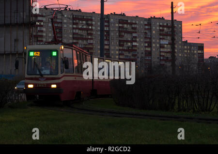 Saint Petersburg, Russia - November 16, 2018: Tram the number 62 with glowing headlights in the morning twilight on the background of the dawn sky. Stock Photo