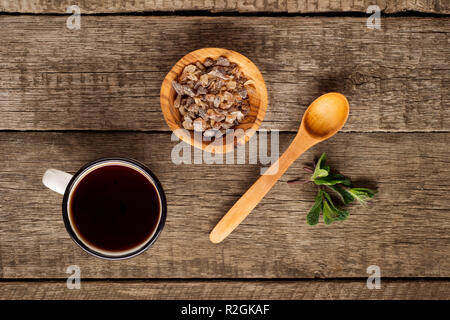 Tea cup with mint leaf and brown sugar in bowl on rustic wooden background. Copy space. Top view Stock Photo