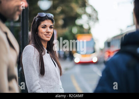 Attractive woman standing outdoors in city, waiting for a tram. Stock Photo