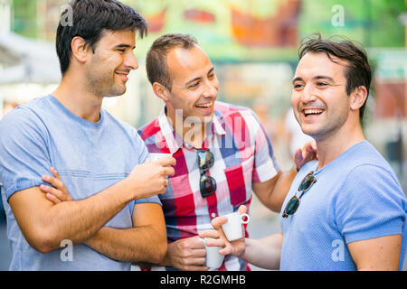 Three friends talking and having fun while drinking coffee outdoor Stock Photo