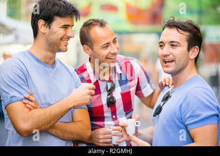 Three friends talking and having fun while drinking coffee outdoor Stock Photo
