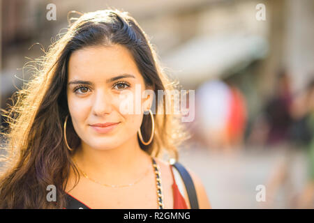 Portrait of young brunette teenager in sunny urban setting Stock Photo