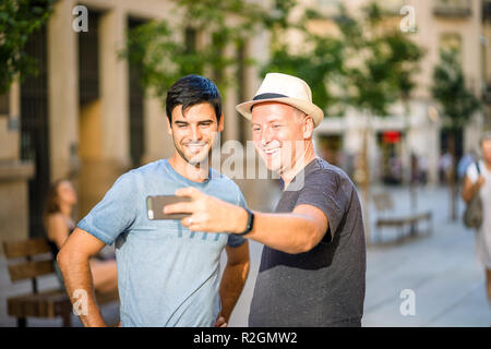 Two male friends taking selfie in the city using smartphone Stock Photo