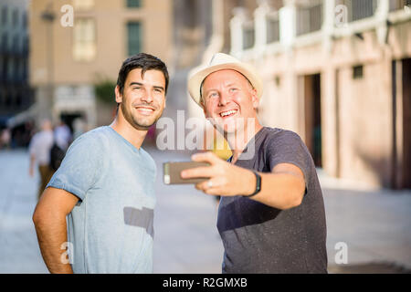 Two male friends taking selfie in the city using smartphone Stock Photo