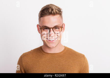 A confident young man in a studio, wearing glasses. Stock Photo