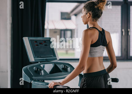 rear view of african american female athlete on treadmill at gym Stock Photo