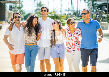 Six friends walking, taking, laughing and having fun during day time in urban setting Stock Photo