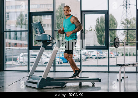 selective focus of african american sportsman running on treadmill at gym