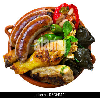 Top view of Bulgarian dish Kapama from mixed stewed meat and sausages with stuffed vegetables served in clayware. Isolated over white background Stock Photo