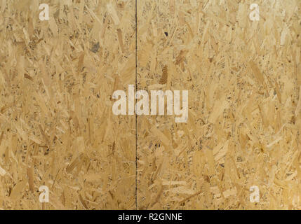 OSB boards are made of brown wood chips sanded into a wooden background. Top view of OSB wood veneer background Stock Photo