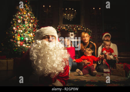 Christmas family portrait in a festive living room with a real Santa Claus.  The atmosphere of celebration and magic. Selective focus. Stock Photo