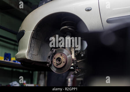 Car brake disk and caliper close up without wheel with white car on backdrop Stock Photo