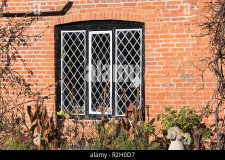 Diamond shaped leaded framed glass window on a wall made of red brick, in the UK. Lead diamond frames windows. Stock Photo