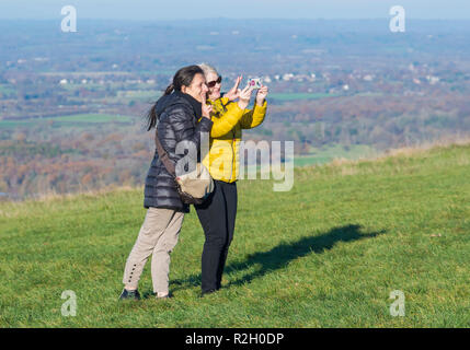 Pair of middle aged female friends taking a selfie photo while making V signs in the British countryside on a hill in the UK. Stock Photo