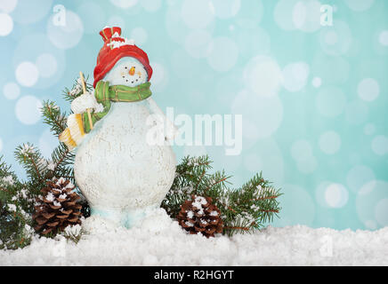 Christnas snowman figurine with pine cones and evergreen branches on a bright colorful background Stock Photo