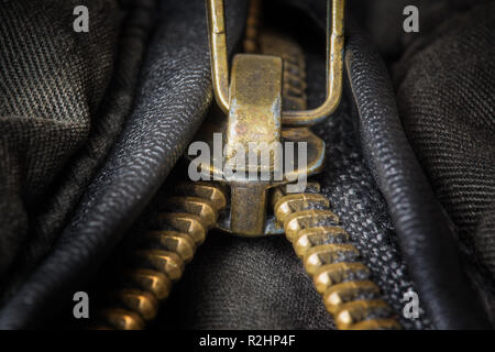 Unzipped brass zipper closeup on dark clothing Stock Photo