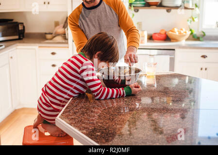 Boy helping his father bake in the kitchen Stock Photo