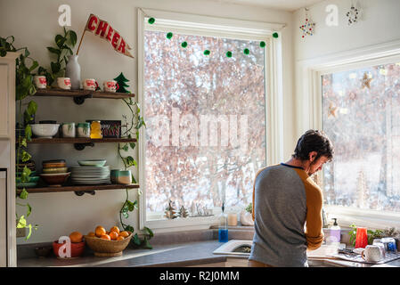 Man standing in the kitchen doing the dishes Stock Photo