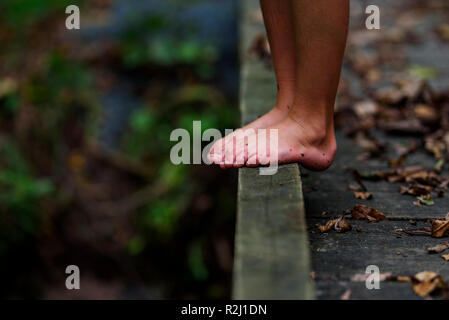 Close-up of a boy's dirty feet standing on a footbridge in the forest, United States Stock Photo