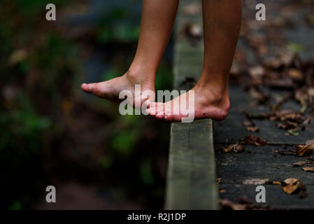 Close-up of a boy's dirty feet standing on a footbridge in the forest, United States Stock Photo