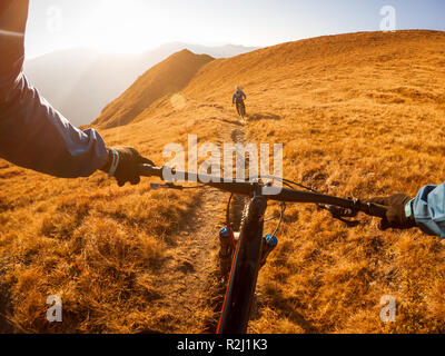 Personal perspective shot of a man mountain biking with a friend in the Alps, Gastein, Salzburg, Austria
