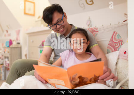 Father and daughter reading book in bedroom Stock Photo