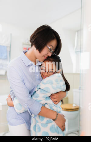 Affectionate mother and daughter hugging in bathroom Stock Photo