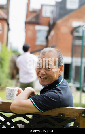 Portrait smiling senior man drinking tea in yard Stock Photo