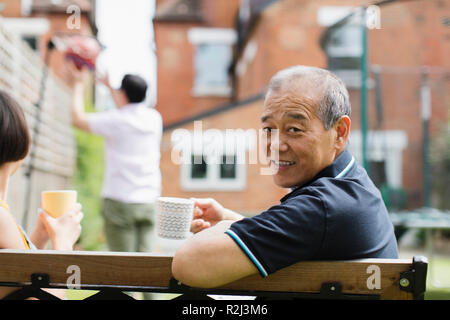 Portrait smiling senior man drinking tea with family in yard Stock Photo