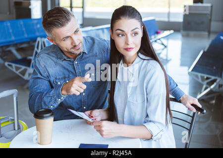 Man pointing at something and woman looking at that in airport Stock Photo
