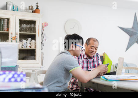 Son helping senior father paying bills at laptop Stock Photo