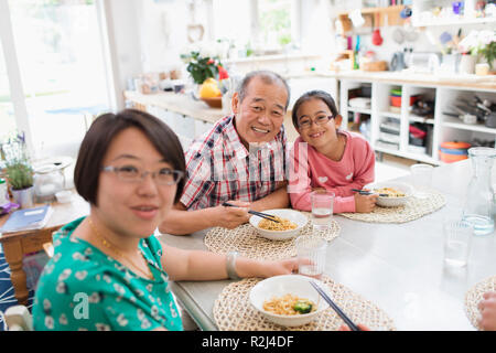 Portrait happy multi-generation family eating noodles with chopsticks at table Stock Photo