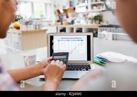 Senior man with calculator looking at investment chart on laptop Stock Photo